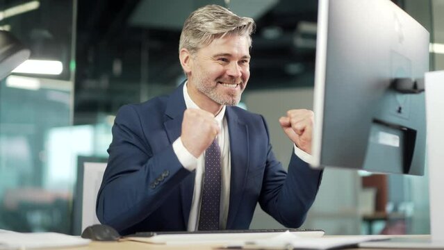 Happy mature bearded Business Man Employee Working on pc computer Celebrates Successful YES Gesture. Working in moderm office Stroke of Luck, Wins Big. Senior worker victory good news financial deal