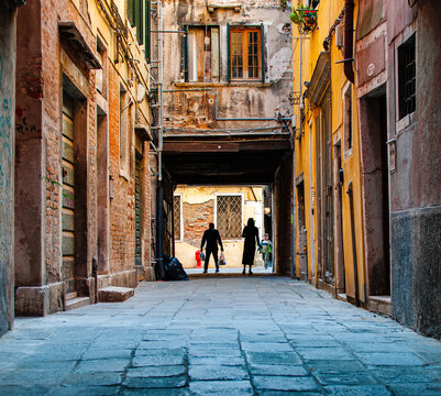 Venetian Street with sun beaming down and silhouetted people