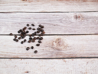Fototapeta na wymiar Close up shot of coffee beans was poured on the wooden floor focus at some point provide bright tones leave a gap on the side shooting in the studio