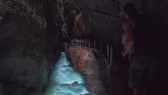 Scenic mountain river at Partnachklamm in Bavaria. Cinemagraph in the Bavarian alps with people walking along the canyon with water rushing. Tourism Garmisch Partenkirchen. 4K UHD seamless video loop.