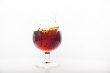 Red wine glass with ice making splash, on white background