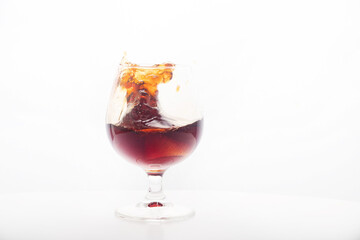 Red wine glass with ice making splash, on white background