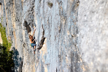 A strong girl climbs a rock