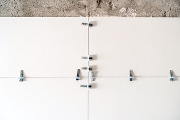 construction site. white modern tiles on bathroom with separator and leveling during works. Home...