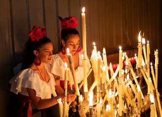 Young couple of girls with piercing dressed as flamenco lights candles as a sign of offering