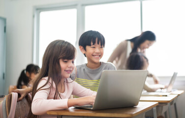 Diverse Multi ethnic of Little girl and boy using laptop Computers in classroom at Elementary school.