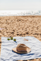 Summer beach accessories on sand background. Holiday travel, tropical concept. Straw hat, sunglasses, towel and fruits. Sun shadow and sunlight