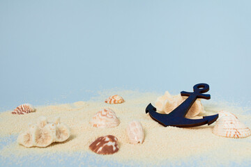 Bright sea sand decorated with shells and anchor on bright blue background. Minimal summer concept....