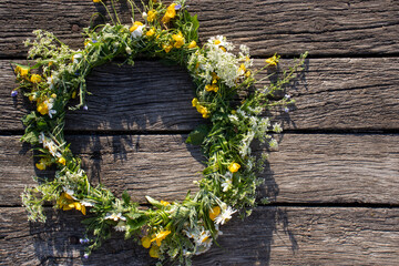 Midsummer crown, wreath of wildflowers on wooden background. Top view, copy space