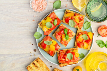 Bruschetta on a toasted baguette with red and yellow tomatoes and basil on a green plate. Healthy Italian snack. Top view. Copy space