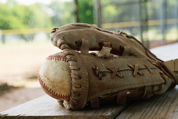 Baseball in glove on dugout bench for ballgame concept during summer.