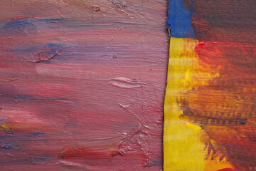 Textured surface in shades of red, pink and blue. On this background lies a caton with an uneven edge painted in red, yellow and blue. Abstract colorful background.