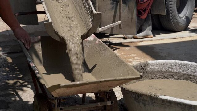 Slow Motion Shot, Pouring concrete from a concrete mixer. Man working with cement mixer. The concrete mix is ​​fed from a concrete mixer at the construction site.