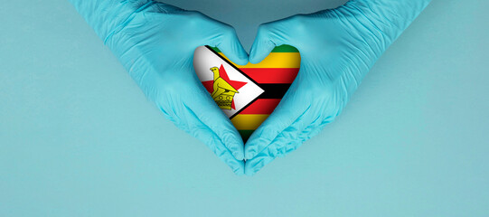 Doctors hands wearing blue surgical gloves making hear shape symbol with zimbabwe flag