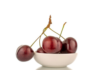 Several sweet cherries with a white ceramic saucer, close-up, isolated on a white background.