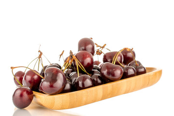 Several sweet cherries on a bamboo plate, close-up, isolated on a white background.