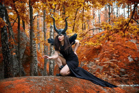 Concept of Halloween and fantasy horror. Cosplay on Maleficent demonic - starring. Face of beautiful woman from a fairytale in autumn forest. Beautiful girl dressed up as devil