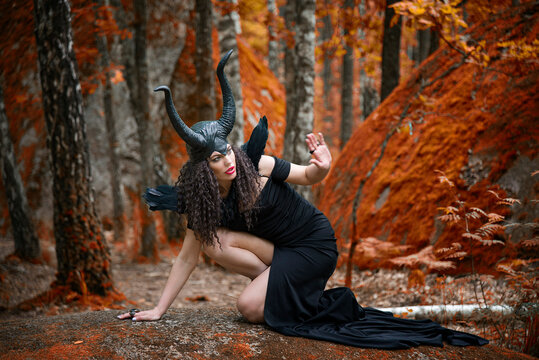 Concept of Halloween and fantasy horror. Cosplay on Maleficent demonic - starring. Face of beautiful woman from a fairytale in autumn forest. Beautiful girl dressed up as devil