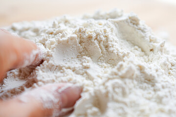 Close-up of flour with hand on wooden table 