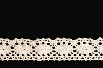 White lace on black background isolated horizontally with copy space. Close up. Sewing concept