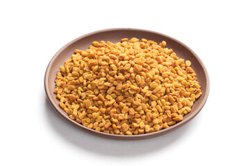 Fenugreek (Trigonella foenum-graecum) in clay plate on white background isolated. Macro. Indian cuisine concept