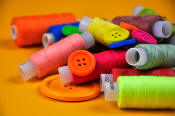Set of multicolored buttons and Spools threads on a yellow background. Blurring.