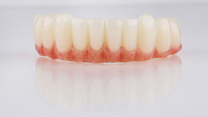 temporary prosthesis made of plastic with artificial gum for the lower jaw on a white background