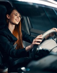 vertical photo of a pleasant, relaxed woman sitting behind the wheel of a car with a seat belt...