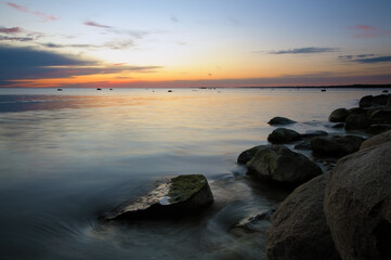 Fototapeta na wymiar Beautiful sunset with smooth sea water surface and stones at night