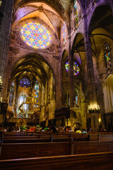 Fototapeta na wymiar Vertical photograph of the rose window in the foreground of the pews inside the cathedral of Mallorca