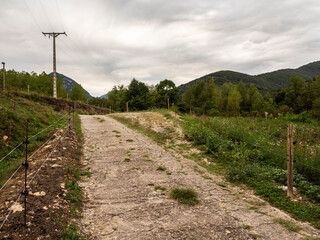 imagen camino de tierra entre prados con una montaña al fondo y el cielo nublado