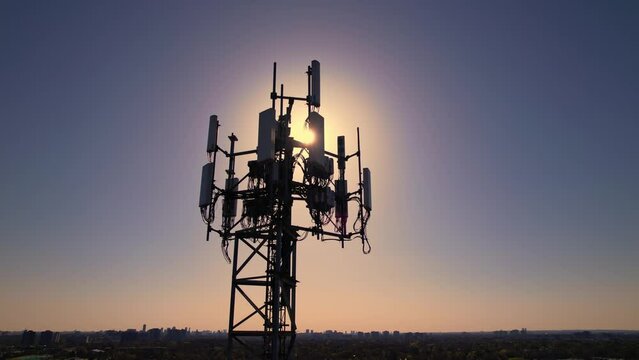 Aerial view of tower antennas with telecommunication, cell phone and radio transmitters. Around view at golden hour evening with sun leaks. Cellular signals for 5g, 4g mobile data and smart phones.