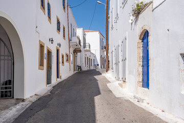 Fototapeta na wymiar Greece, Kythira island. Empty narrow street at Chora town. Traditional white color wall building
