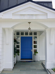 front porch of modern white farmhouse with blue door