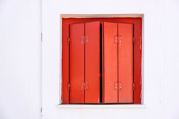 Window red closed wood shutter on white wall. Cyclades house front view, Greek island