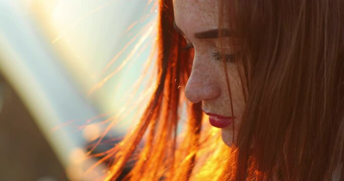 close up profile of serious face of red haired young woman with freckles.