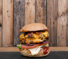 Monster burger. Closeup view of a multilayer burger with two meat medallions, cheddar cheese,...