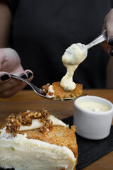 Eating dessert. Closeup view of a woman's hand holding a spoon with carrot cake and passion fruit mousse. 
