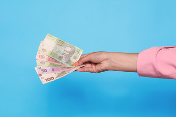 Hand holding ukrainian hryvnia currency over blue background