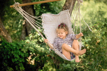 little girl is swinging in a hammock and smiling 
