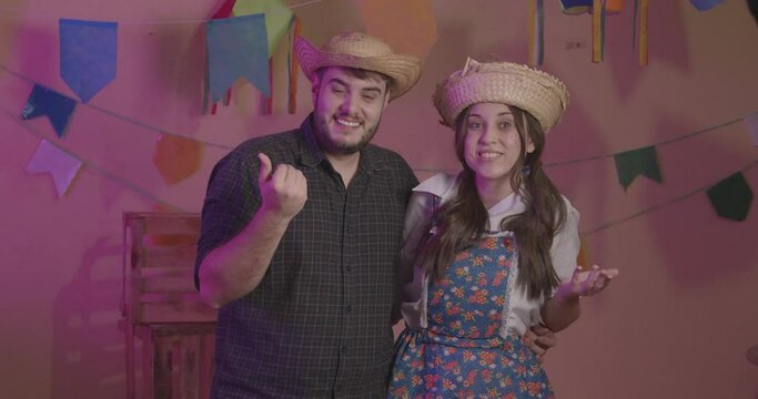 Beautiful couple wearing typical clothes for the Festa Junina. Calling with the hands. inviting.