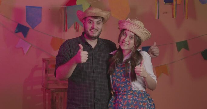 Beautiful couple wearing typical clothes for the Festa Junina. Thumb, positive, affirmative. approval.