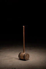 Large wooden circus mallet on concrete aged with rusty steel ring