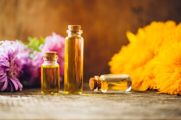 oils with flowers. Oil bottle. Flowers. Wooden table. Photo. Background. Bottle. Aroma.