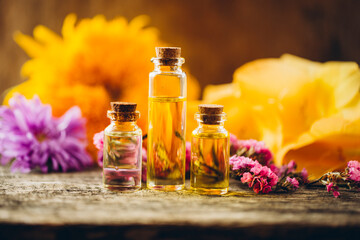 oils with flowers. Oil bottle. Flowers. Wooden table. Photo. Background. Bottle. Aroma.