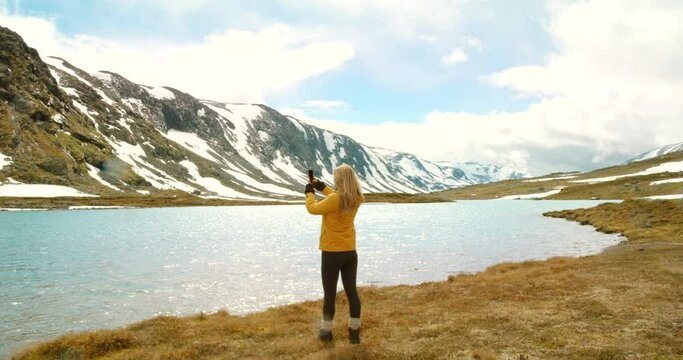 4k video footage of an unrecognisable woman standing and using her cellphone to photograph the lake in Mre og Romsdal