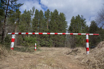 Fototapeta na wymiar The barrier is red and white, prohibiting entry into the forest.