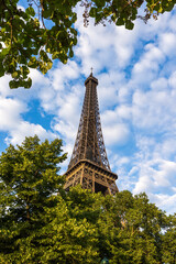 Partie supérieure de la Tour Eiffel devant un ciel partiellement nuagueux