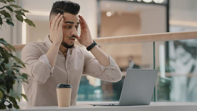 Bearded arabian indian man worker manager freelancer reading bad news in laptop worried with email shock stress of getting unpleasant news has business failure receiving dismissal notice lost job