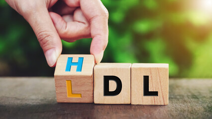 Hand flipping wooden cube block from change LDL to HDL for High is high density lipoprotein and LDL is low density lipoprotein concept on nature background.                          